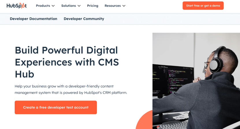 Developer working on computer with HubSpot CMS tools displayed on screen.