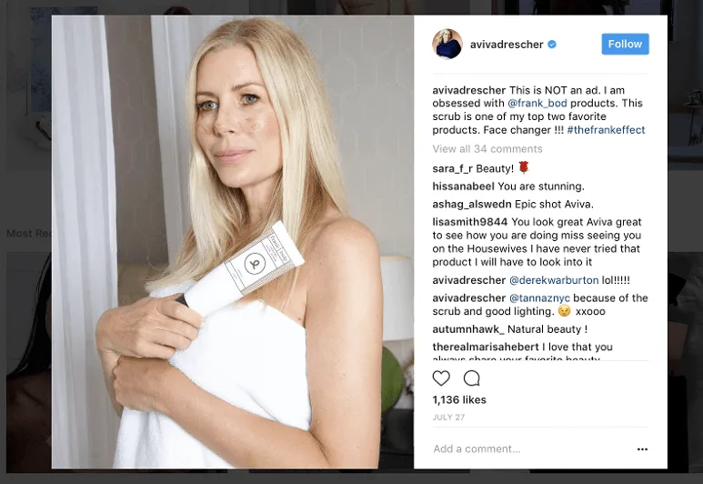 Woman holding skincare product wrapped in a white towel in a bathroom.