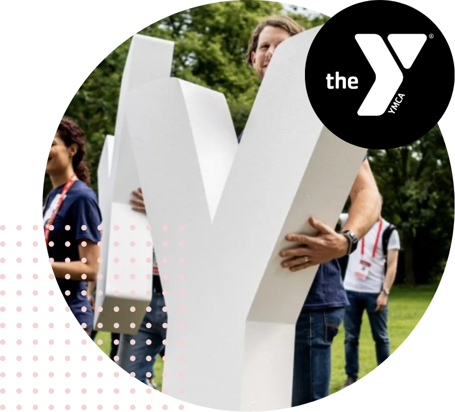 People holding large YMCA letters outdoors at an event.